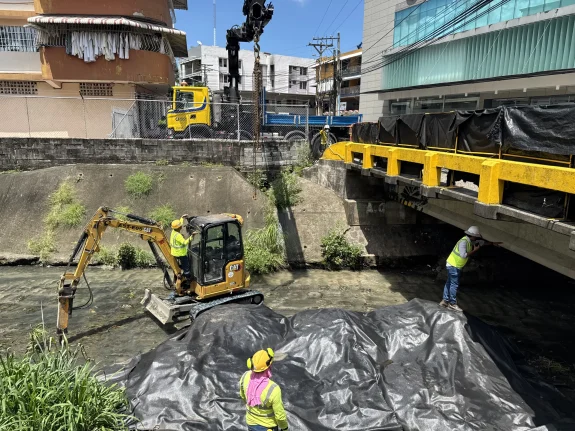 Grúa bajando una excavadora al cauce para una obra de saneamiento de ríos en Panamá