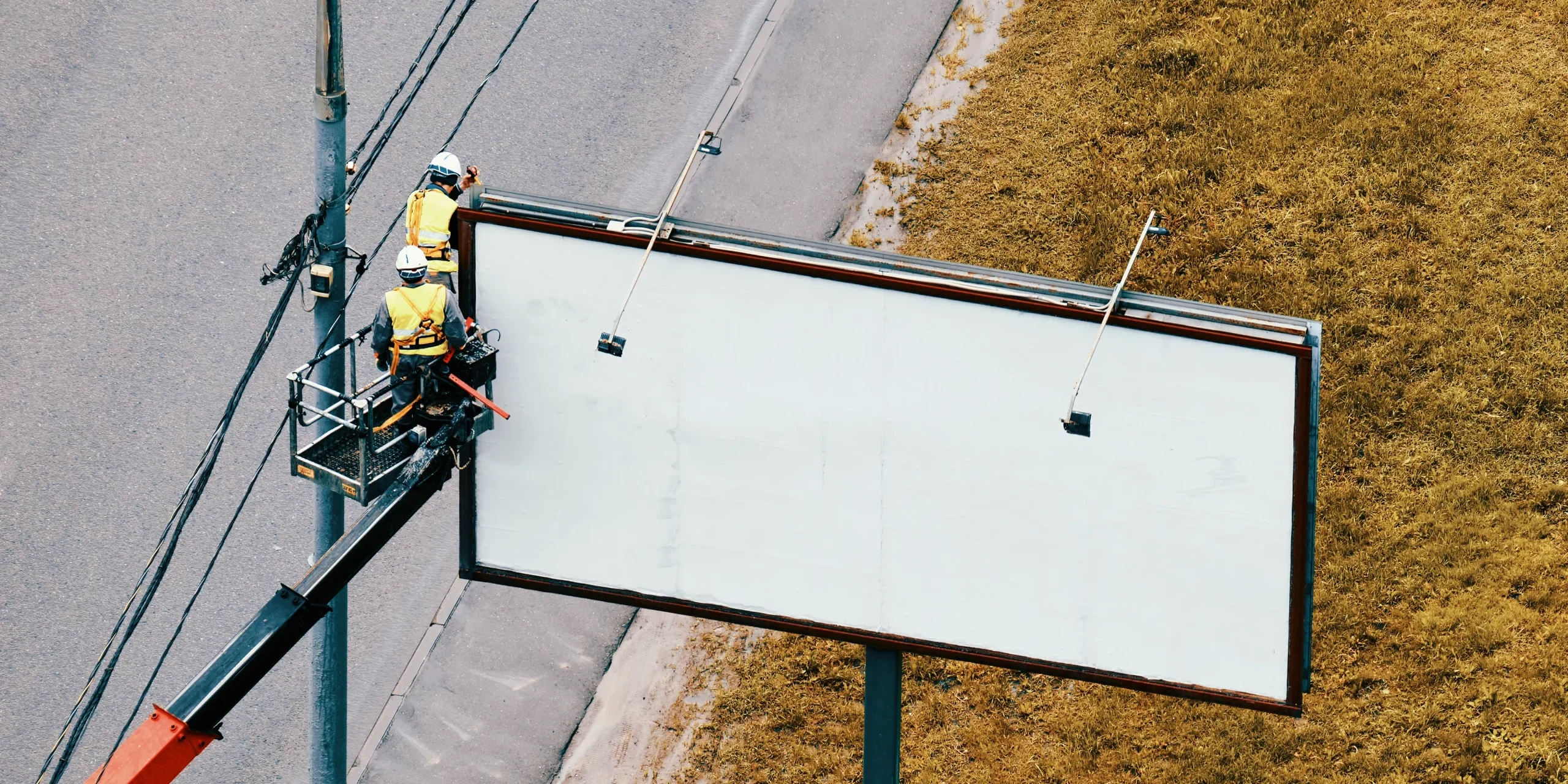workers-hang-a-roadside-poster-on-a-billboard-near-2026-03-26-08-10-51-utc (1) Grúas para instalar vallas publicitarias en Panamá durante el montaje de una valla junto a una carretera